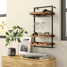 a shelf with wine glasses on it next to a potted plant