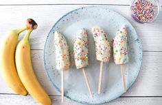 bananas and sprinkles are on a plate next to some ice cream pops