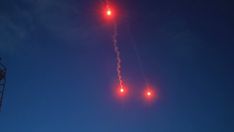 an airplane is flying high in the sky with red lights on it's tail