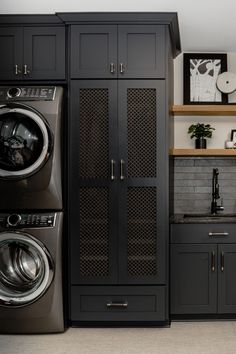 a washer and dryer sitting next to each other in a room with black cabinets