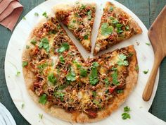 a pizza sitting on top of a white plate next to a wooden spoon and knife