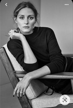 a black and white photo of a woman sitting in a chair with her hand on her chin