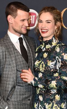 a man in a suit and tie standing next to a woman wearing a floral dress