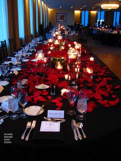 a long table is set with candles and red poinsettis for an elegant dinner