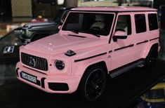 a pink mercedes g - class suv is on display