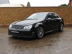 a black car parked in front of a brick wall