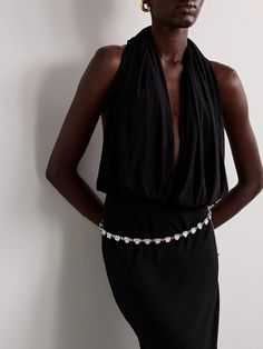 a woman wearing a black dress and headpiece standing in front of a white wall