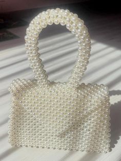 The pearl bag with round handle and magnetic clasp has an elegant and modern design. The round handle provides comfortable carrying, and the magnetic clasp provides easy access to the contents of the bag and a secure closure. The inner lining material provides additional protection and comfort. Cream Bags With Pearl Handle For Spring, Chic Shoulder Bag With Pearl Handle For Spring, Spring Cream Bags With Pearl Handle, Elegant Cream Bag, Elegant Cream Bags, Chic Shopping Bag With Pearl Handle, Elegant Clutch As Fashion Accessory For Spring, Elegant Spring Fashion Accessory Clutch, Spring Pearl Handle Tote Shoulder Bag