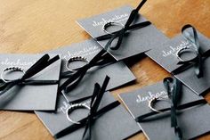 several pieces of black paper tied to each other with silver rings and ribbons on them