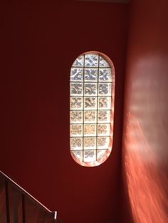 a red wall with a round window in the center and stairs leading up to it