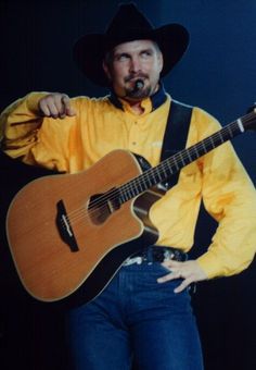 a man wearing a cowboy hat and holding a guitar