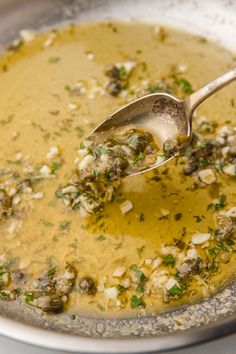 a spoon is full of soup in a silver bowl with parsley on the side