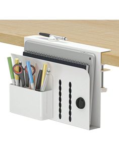 a white desk organizer with pens and pencils in it