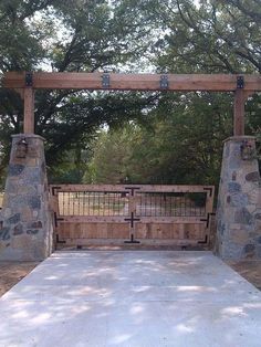 a gated in area with stone pillars and gates on both sides, surrounded by trees