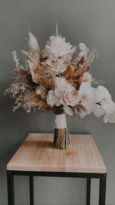 a bouquet of flowers sitting on top of a wooden table next to a gray wall