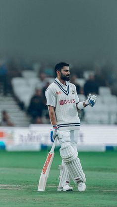 a man holding a cricket bat on top of a field