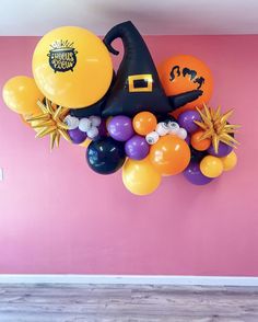 balloons and decorations in the shape of a witch's hat on a pink wall