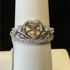 This Beautiful Sterling Silver Ring Features A Heart-Shaped Champagne Topaz As The Main Stone, Surrounded By Sparkling White Topaz Stones. The Ring Is Perfect For Any Special Occasion, Such As An Engagement, Graduation, Or Birthday. It Has A Total Carat Weight Of 0.90 And Is Set In A Bezel Style. The Ring Is A Size 6 And Has A Weight Of Approximately 2.8g. It Is Made Of 925 Silver And Has A Beautiful White Color. The Ring Is Not Sizable And Has A Band Style. It Is A Perfect Gift For Someone You Diamond White Solitaire Heart Ring For Anniversary, White Gold Topaz Birthstone Ring For Anniversary, Moissanite Heart Ring With Center Stone For Promise, Moissanite Heart Cut Jewelry For Promise, Anniversary White Gold Birthstone Ring With Topaz, Heart Cut Cubic Zirconia Ring With Center Stone, Anniversary Heart Cut Ring With Prong Setting, Heart Cut Moissanite Jewelry For Promise, Heart Cut Topaz Jewelry For Anniversary