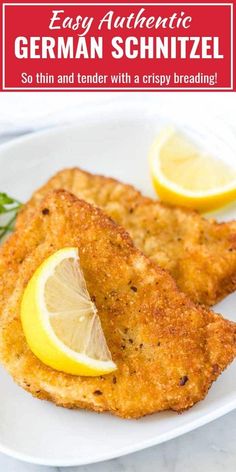 two fried fish fillets on a white plate with lemon wedges and parsley