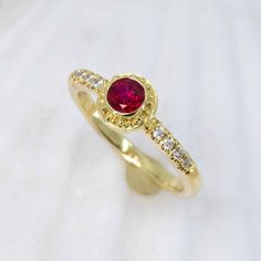 Treat yourself to an exquisite adornment handcrafted in 18K granulated gold, showcasing a stunning ruby and glittering diamonds, to add a hint of sophistication and charm to any outfit. The classic simplicity of this Ruby & Diamond Classical Ring will add an elegant allure to your jewelry collection. Featuring a dazzling 0.58ct ruby accented with 0.1cttw of 1.5mm VS/GH diamonds. Size 6, but each ring comes with free sizing and FREE SHIPPING! Watch a video of this ring being made HERE Unsure what Ruby Rings With Pave Setting, Ruby Ring With Diamond Pavé Setting, Ruby Ring With Pave Setting And Diamond, Gold Ruby Rings With Pave Setting, Luxury Yellow Gold Ruby Ring With Single Cut Diamonds, Ruby Rings With Single Cut Diamonds, Gold Ruby Jewelry With Pave Setting, Yellow Gold Ruby Rings With Pave Setting, Ruby Rings With Round Cut Single Diamonds