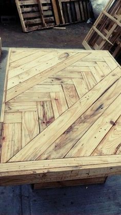 an outdoor table made out of pallets and wooden planks is sitting on the ground