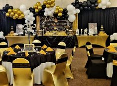 a room filled with black and white tables covered in gold and silver chairs, balloons and tablecloths