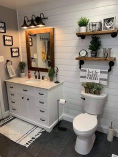 a white toilet sitting next to a sink in a bathroom under a wooden framed mirror