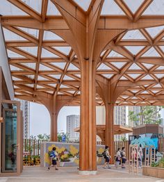 people are walking around in an open area with wooden structures and colorful paintings on the walls