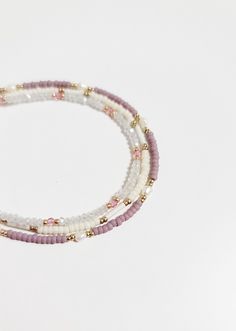 three beaded bracelets with pink, white and gold beads on a white background