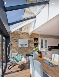 a dining room table with white chairs under a skylight