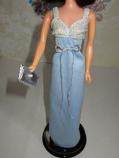 a doll wearing a blue dress holding a purse