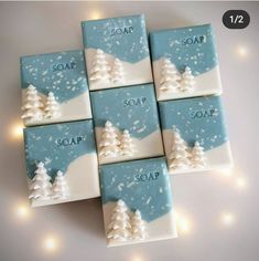 four soap bars decorated with snow trees and the words soap on them are surrounded by lights