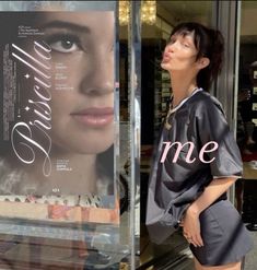 a woman standing in front of a store window with her hands on her hips and looking up