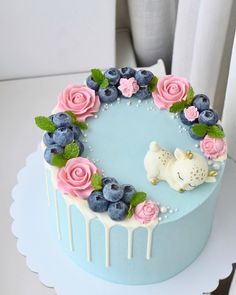 a cake decorated with blueberries, pink roses and white icing on a table