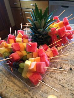 fruit skewers are arranged on top of a granite countertop in front of a pineapple