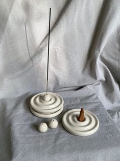 a white sculpture with three balls and a stick sticking out of it's center