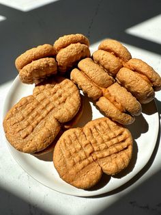 several cookies on a white plate sitting on a table with the sun shining through them