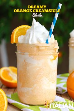 two mason jars filled with whipped cream and oranges on a table next to an orange slice