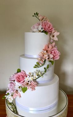 a three tiered white cake with pink flowers on top