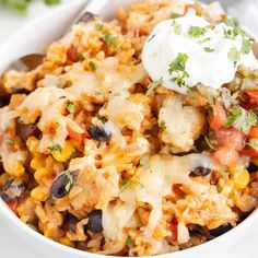 a white bowl filled with mexican rice and black beans, topped with sour cream on top