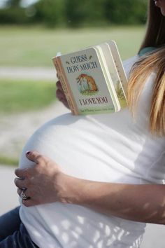 a pregnant woman reading a book about how to grow mom much while holding her belly