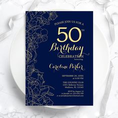 a blue and gold 50th birthday party card on a white plate with silver foil flowers