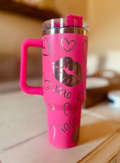 a pink travel mug sitting on top of a table