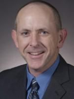 a man in a suit and tie smiling at the camera