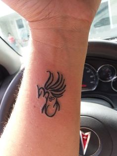 a small tattoo on the wrist of a person in a car with a steering wheel