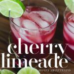 two glasses filled with cherry limeade sitting on top of a wooden table