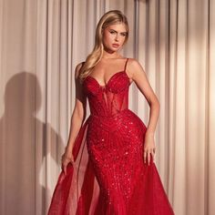 a woman in a red gown posing for the camera with her hands on her hips