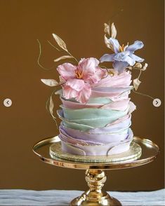 there is a multi layer cake with flowers on the top and bottom, sitting on a gold platter