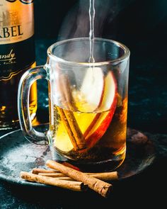 an apple cider being poured into a glass mug