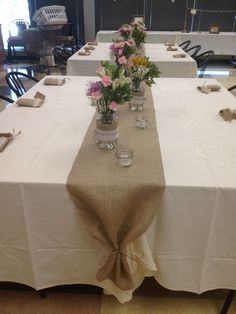 the table is set with mason jars and flowers